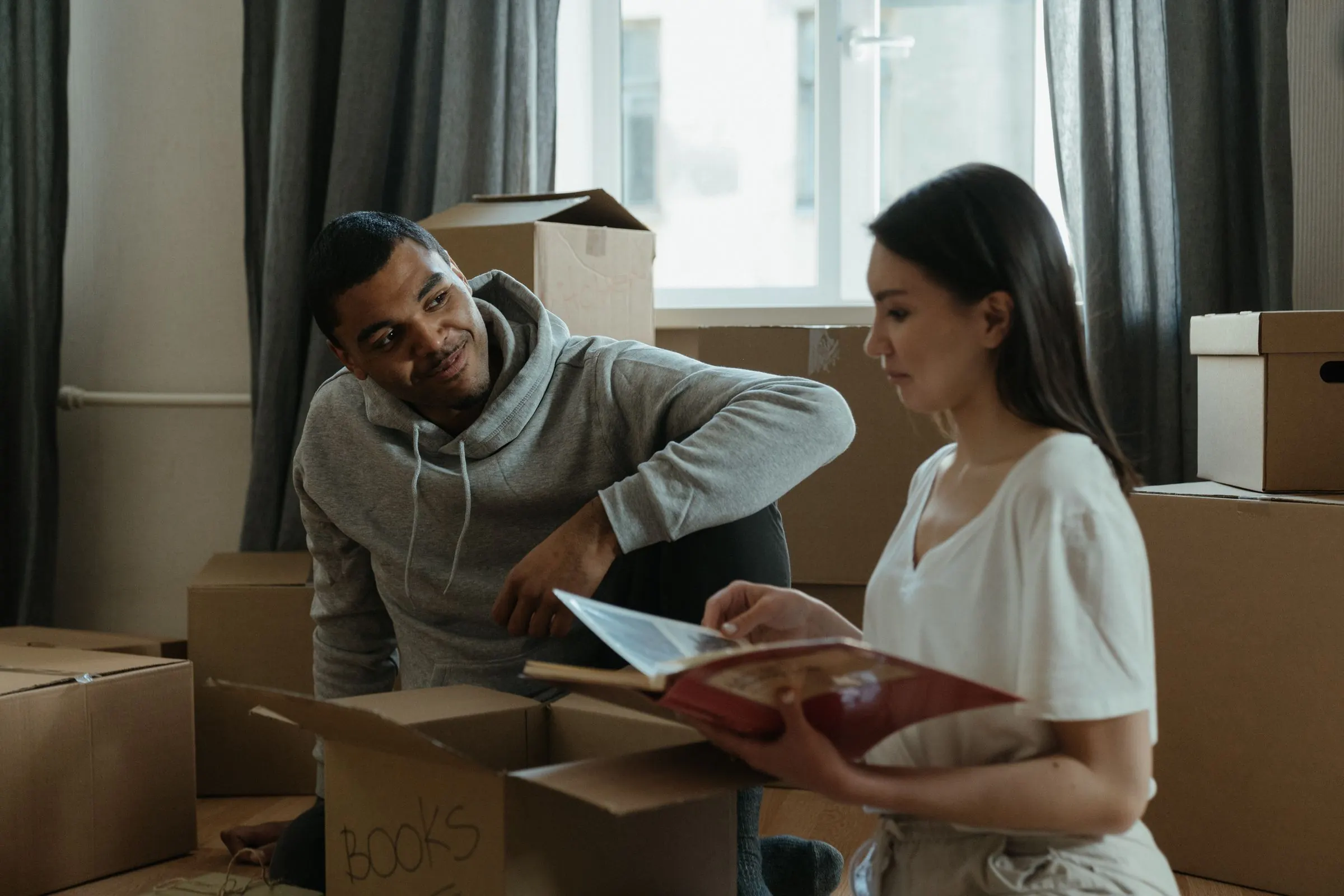 Pareja revisando papeles entre cajas de mudanza en su casa.