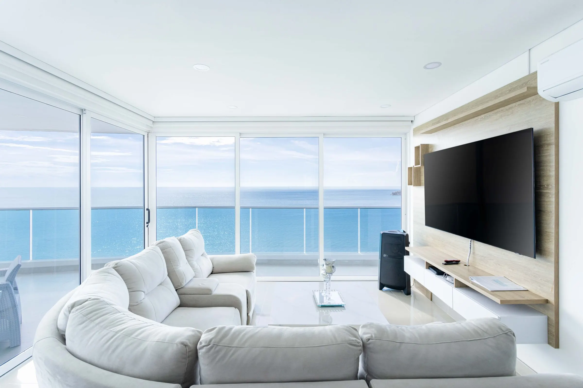 Sala de un apartamento luminoso con ventanales frente al mar.