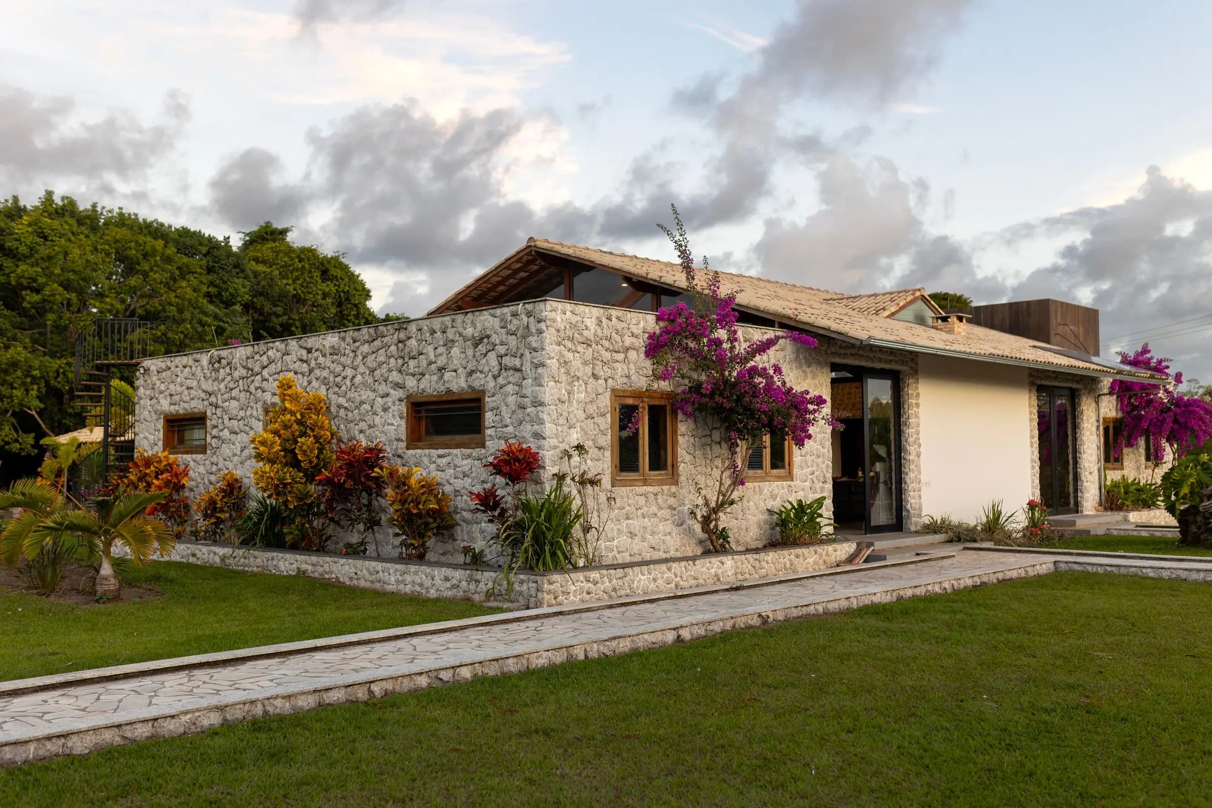 Casa de piedra de una planta con jardín y flores.